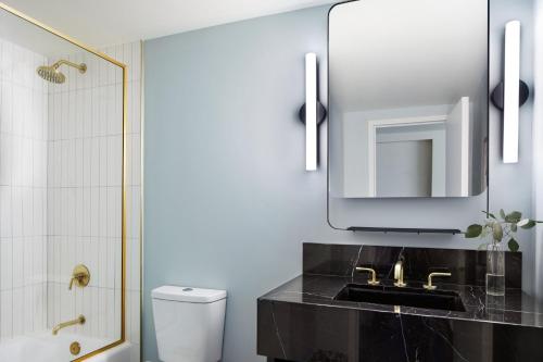 a bathroom with a sink and a mirror and a toilet at Kimpton Alton Fisherman's Wharf by IHG in San Francisco