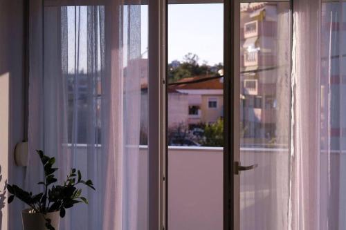 a window with white curtains and a plant next to it at East Coast Senses in Thessaloniki