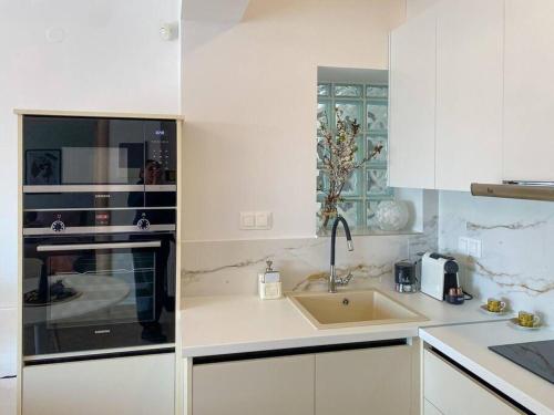 a white kitchen with a sink and a microwave at East Coast Senses in Thessaloniki