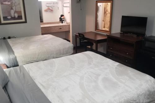 a hotel room with two beds and a desk and a mirror at Hotel 2 Queen Beds Hotel Room 220 Booking in Stillwater