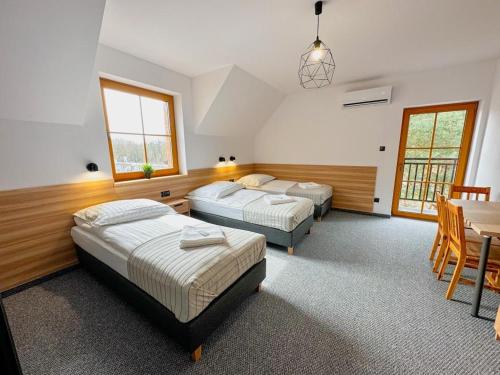 two beds in a room with a table and chairs at Hotel Czerwone Korale in Cielimowo