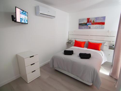 Dormitorio blanco con cama con almohadas rojas en BUNGALOW CAMPO DE GOLF, en San Bartolomé