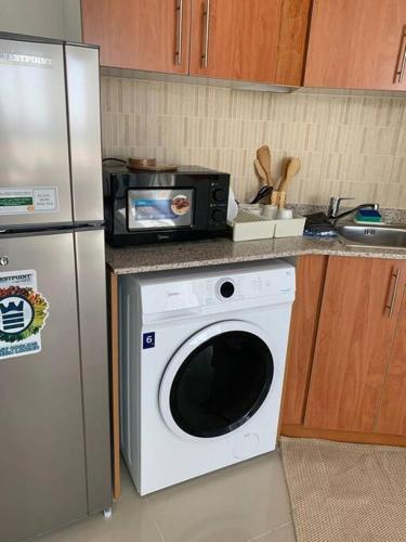 a kitchen with a microwave and a washing machine at One Bedroom Apartment- IMPZ in Dubai