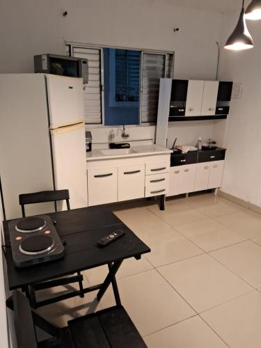 cocina con armarios blancos, mesa y nevera en Minha casa sua casa completa, en Guarulhos