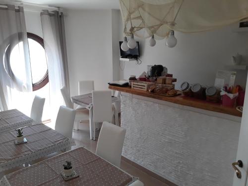 a kitchen with white chairs and a table and a window at Sweet Suite Margherita B&B in Margherita di Savoia