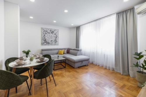 a living room with a couch and a table and chairs at Apartment Marina in Novi Sad