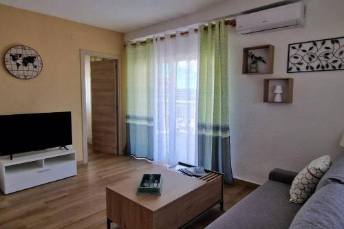 a living room with a couch and a tv at Incredible seafront with sunrise and sunset views in Benicàssim