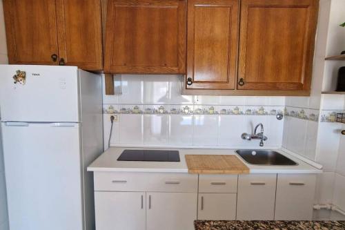 a kitchen with a white refrigerator and a sink at Incredible seafront with sunrise and sunset views in Benicàssim