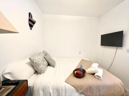 um quarto com uma cama branca e uma televisão na parede em Apartamento estilo árabe en el centro De San Pedro de Alcántara - Toledo 1b em Marbella