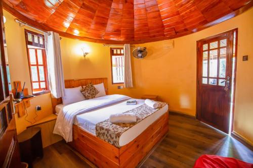 a bedroom with a bed with a wooden ceiling at Tea Cabins in Ella