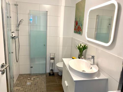 bagno con lavandino e doccia in vetro di Helles Apartment über den Dächern Rostocks a Rostock