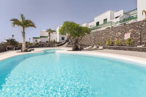 una grande piscina blu di fronte a un edificio di Apartamento OM con piscina y vistas al mar a Costa Teguise