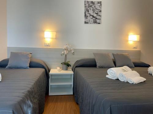 two beds in a room with towels on them at Hotel Augustus in Milano Marittima