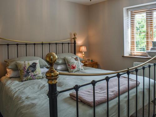 a bedroom with a metal bed with pillows at Mudhorse Cottage in Stolford