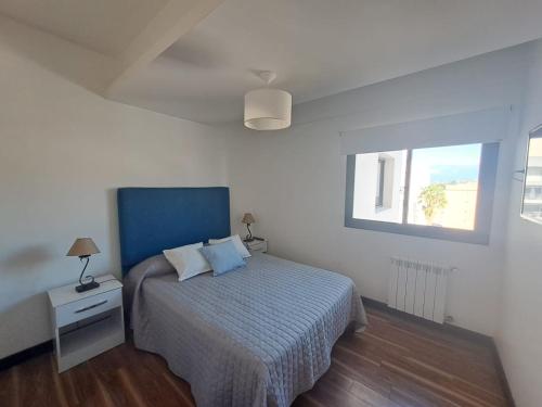 1 dormitorio con 1 cama con cabecero azul y ventana en Departamento Céntrico II en Salta