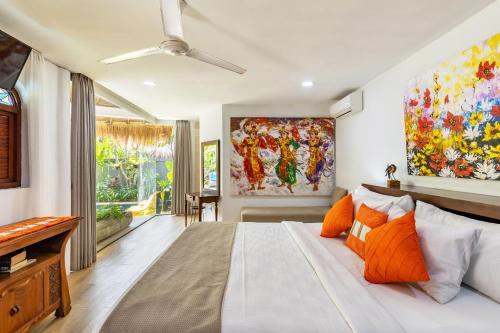 a bedroom with a large bed with orange pillows at Elina Villas in Seminyak