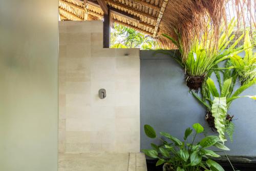 a bathroom with plants on the side of a wall at Elina Villas in Seminyak