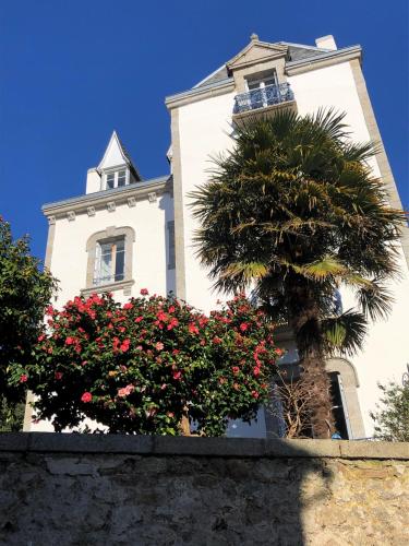 a tall white building with a palm tree and flowers at Maison Castel Braz in Pont-Aven