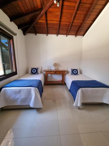 a room with two beds and a wooden ceiling at Casa Aprazível no Alto de Búzios in Búzios