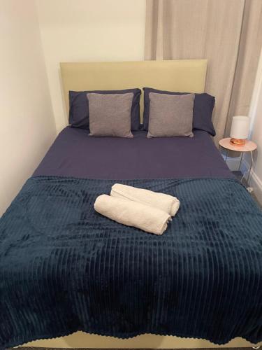 ein Bett mit einer blauen Decke und zwei Handtüchern darauf in der Unterkunft Room in Gloucester Road 4 in Bristol