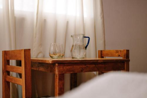 a table with two glasses and a vase on it at SIGRUM Hostel in San Rafael