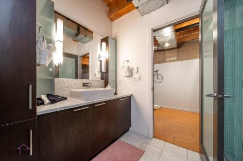 W łazience znajduje się umywalka i lustro. w obiekcie Historic JD Loft, Near ICE District, Rogers Place, UG Parking w mieście Edmonton