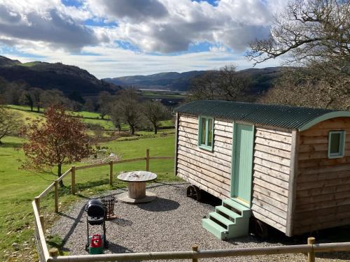a small cabin with a table and a fence at Shepherds hut above mawddach estuary in Dolgellau