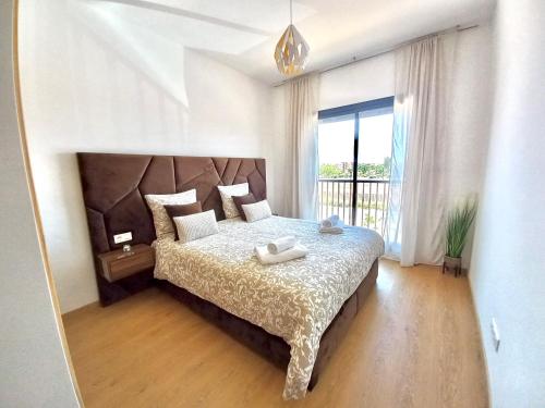 een slaapkamer met een groot bed en een groot raam bij Magnifique appartement Résidence DOMAINE DE NORIA in Marrakesh