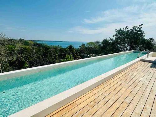 a swimming pool with a wooden deck and the ocean at Micaela Bacalar C2 Depto de lujo Vista Laguna in Bacalar