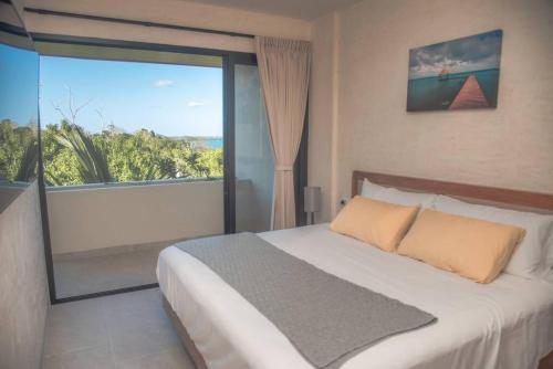 a bedroom with a large bed and a large window at Micaela Bacalar C2 Depto de lujo Vista Laguna in Bacalar
