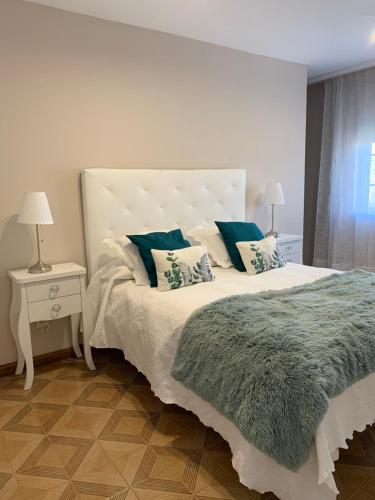 a bedroom with a large white bed with blue pillows at Fogar de Aurora in Portomarin