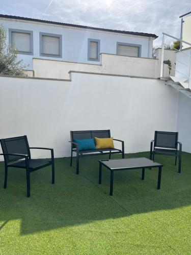 three chairs and a table on the grass in front of a building at Fogar de Aurora in Portomarin
