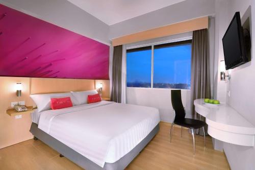 a hotel room with a large bed and a desk at favehotel Jababeka Cikarang in Cikarang
