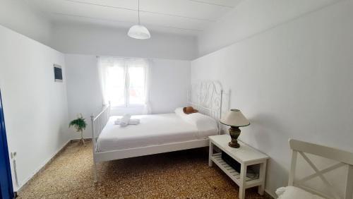 a white bedroom with a white bed and a lamp at Blue and White in Kremasti