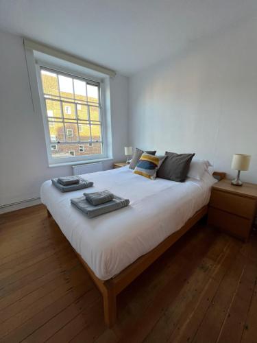 Schlafzimmer mit einem großen weißen Bett und einem Fenster in der Unterkunft Cosy London bedroom near Oval Station - shared bathroom in London