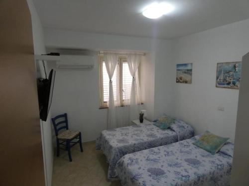 a bedroom with two beds and a chair and a window at Playa Bonita Relax House in Scilla