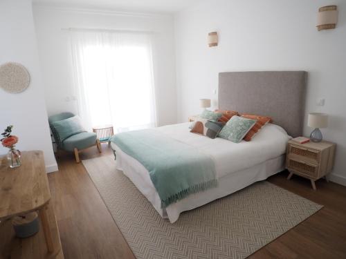 um quarto com uma cama grande e uma cadeira em Charming V2 next to ocean, golf & natural reserve em Albufeira