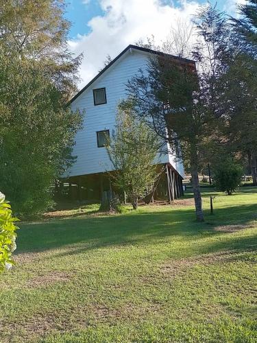 a large white barn with a tree in the yard at Cabañas Wualmapu " acceso sólo vehiculos tipo camioneta, jeep o SUV" in Pucón