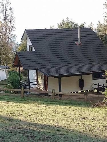 a house with a black roof and a fence at Cabañas Wualmapu " acceso sólo vehiculos tipo camioneta, jeep o SUV" in Pucón
