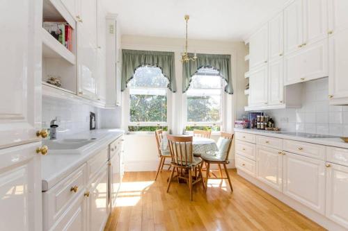 a kitchen with white cabinets and a table and chairs at Large 3 bed flat in central Wimbledon in London