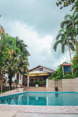 a swimming pool in front of a house with palm trees at Albergue Turístico Gstir in Pozuzo
