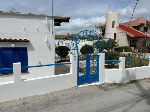 a white house with a blue door and a building at Blue and White in Kremasti