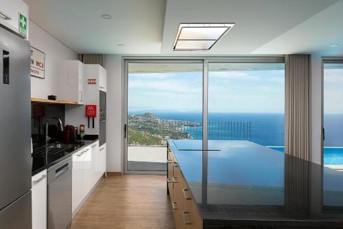 a kitchen with a counter with a view of the ocean at Peak A Boo Private Heated Pool and Private Parking in Câmara de Lobos