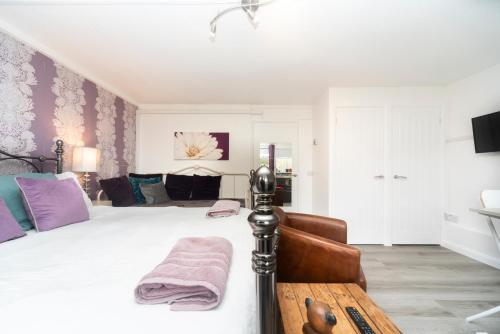 1 dormitorio con 1 cama blanca grande con almohadas moradas en 11 Boutique studio apartment perfect for peaceful getaway, secluded garden, quiet location, en High Wycombe