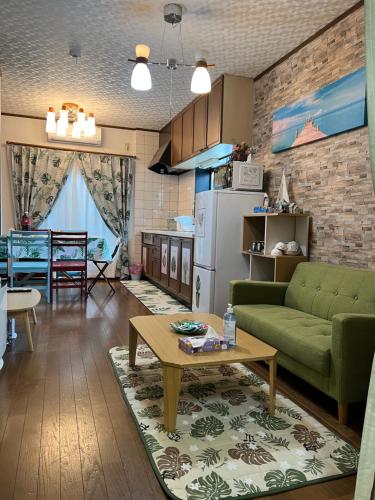 een woonkamer met een groene bank en een tafel bij 舟荘 in Osaka