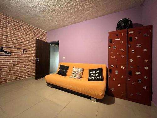 un sofá naranja con almohadas en una habitación en DICI Coliving Housing The Friends Room, en Cabo San Lucas