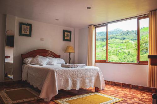 een slaapkamer met een bed en een groot raam bij Albergue Turístico Gstir in Pozuzo