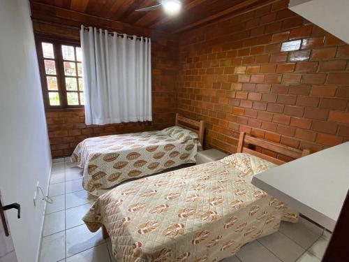 a bedroom with two beds and a brick wall at Lindo chalé em Gravatá - Condomínio Mont Blanc V in Gravatá
