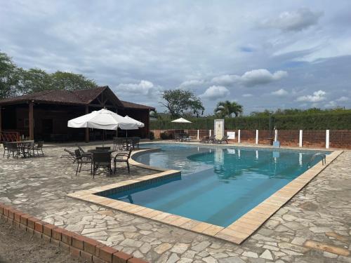 a swimming pool with tables and chairs and an umbrella at Lindo chalé em Gravatá - Condomínio Mont Blanc V in Gravatá