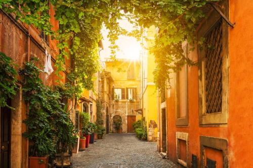 an alley in an old town with the sun shining at ETERNA Trastevere Apartment in Rome